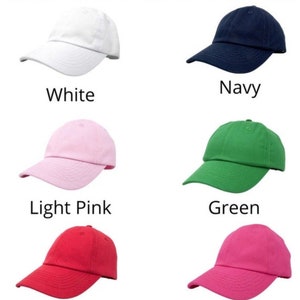 May include: Six different coloured children's baseball caps. The caps are white, navy, light pink, green, red, and hot pink.
