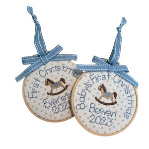 Pode incluir: Dois enfeites de Natal personalizados azuis e brancos com um design de cavalo de balan&ccedil;o. Os enfeites dizem "Baby's First Christmas" e incluem os nomes "Everett 2021" e "Bowen 2023".