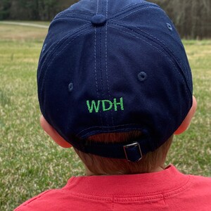 Op de afbeelding: Een donkerblauwe baseballpet met een groen geborduurd logo met de tekst "WDH".