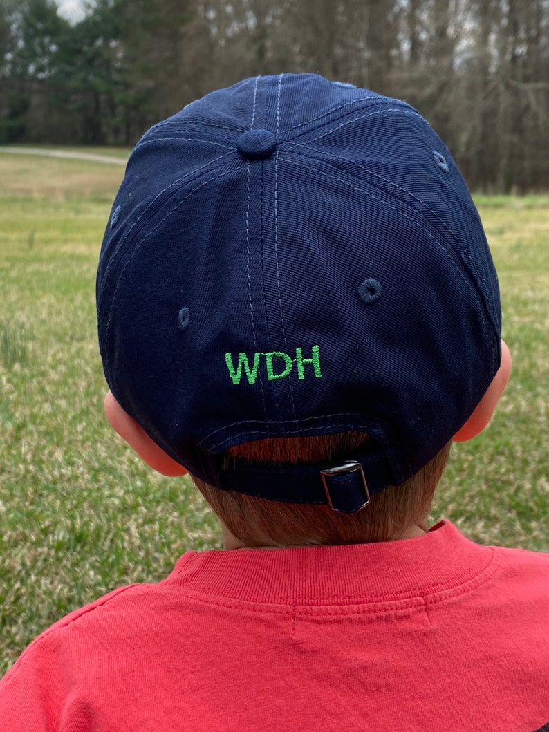 Op de afbeelding: Een donkerblauwe baseballpet met een groen geborduurd logo met de tekst "WDH".