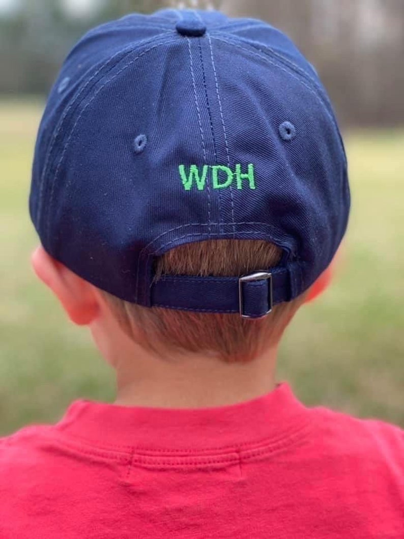 May include: A navy blue baseball cap with an adjustable strap at the back. The cap has green embroidery that reads "WDH".