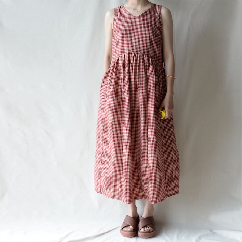 May include: A red and white gingham sleeveless dress with a gathered waist and pockets. The dress is midi length and has a v-neckline.