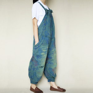 May include: A blue denim overall with a tie at the waist and a floral pattern. The overall has pockets on the front and is cuffed at the ankles.