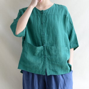 May include: A teal linen button-down shirt with two patch pockets. The shirt has a relaxed fit and short sleeves.