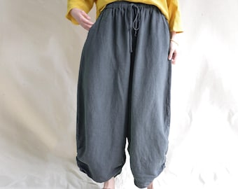 May include: Gray linen pants with a drawstring waist. The pants are wide-legged and have a relaxed fit.
