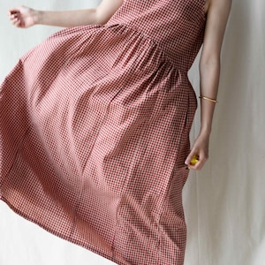 May include: A red and white gingham sleeveless dress with a v-neckline. The dress has a gathered waist and a midi length.