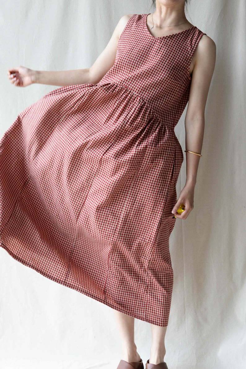 May include: A red and white gingham sleeveless dress with a v-neckline. The dress has a gathered waist and a midi length.