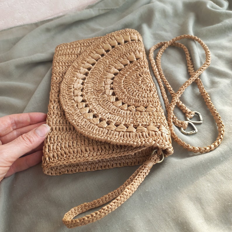 Puede incluir: Un bolso de crochet de color marr&oacute;n claro con un dise&ntilde;o circular y una correa larga. El bolso est&aacute; hecho de materiales naturales y tiene un estilo casual y bohemio.
