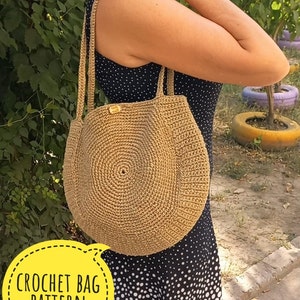 May include: A crocheted tote bag made of natural fiber, with a round bottom and two long straps. The bag is a light brown color and has a small "HAND MADE" tag attached to it. The bag is being held by a person wearing a black and white polka dot dress.