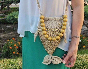 Può includere: Una borsa a tracolla a forma di pesce realizzata in filo di cotone beige all'uncinetto e linguette di lattine in metallo dorato. La borsa presenta un manico composto da grandi perle dorate opache, una catena dorata e una coda all'uncinetto.