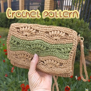 May include: A crocheted clutch in shades of tan and green, with a floral pattern. The clutch has a wrist strap and a zipper closure. The text "Crochet pattern" is displayed at the top of the image.