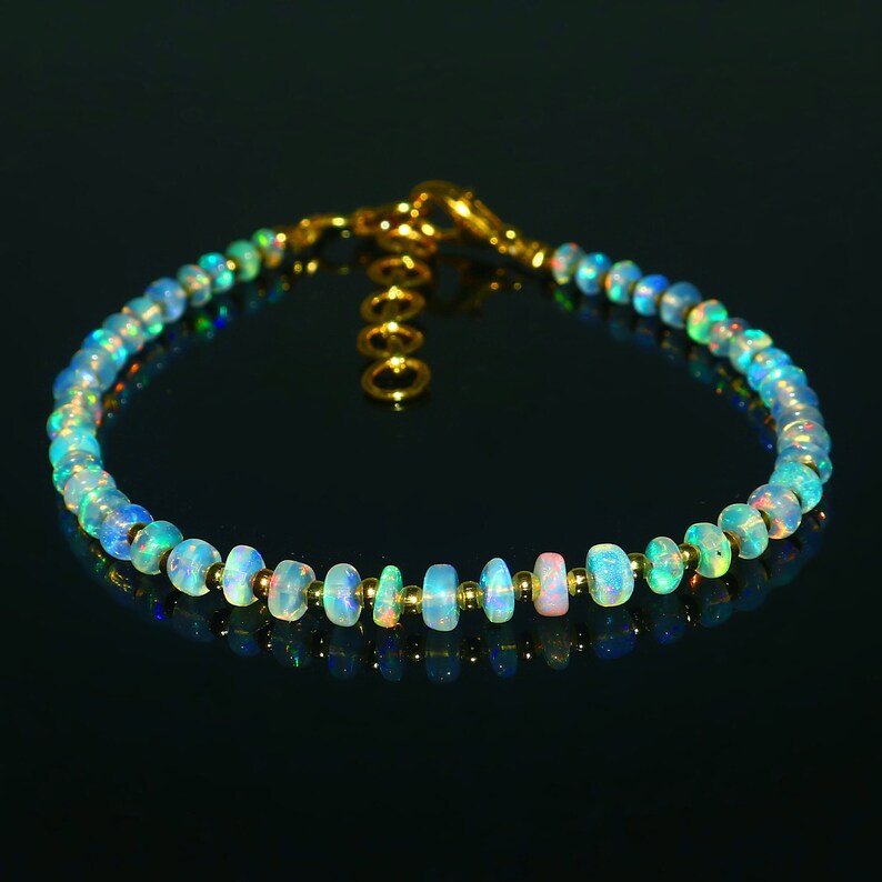 May include: A delicate bracelet made with iridescent opal beads and gold accents. The bracelet is approximately 7 inches long and features a lobster clasp closure.