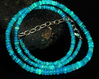 May include: A turquoise blue opal beaded necklace with a silver chain clasp. The necklace is made of small, round beads and is layered for a more substantial look.
