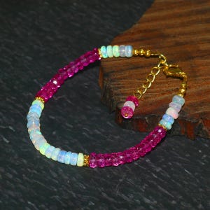 May include: A pink and white gemstone bracelet with a gold clasp. The bracelet is made of small, round beads.