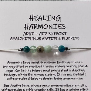 May include: A bracelet featuring blue, green, and white stones. The bracelet is made with amazonite, blue apatite, and fluorite. The card reads "Healing Harmonies, ADHD-ADD Support, Amazonite Blue Apatite & Fluorite".