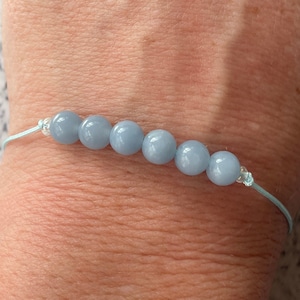 Peut inclure: Un bracelet bleu clair avec des perles rondes en agate bleue.