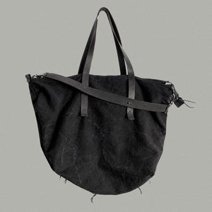 May include: A black tote bag with two top handles and a detachable shoulder strap. The bag features a textured fabric body and measures 66 cm wide at the top, 47 cm in height, and 20 cm in depth. The text M51 is visible at the top right corner.