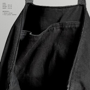 May include: Black denim canvas tote bag with a full-grain leather strap. The bag has a width of 66 cm, a height of 47 cm, and a depth of 28 cm. The bag features a pocket on the front.