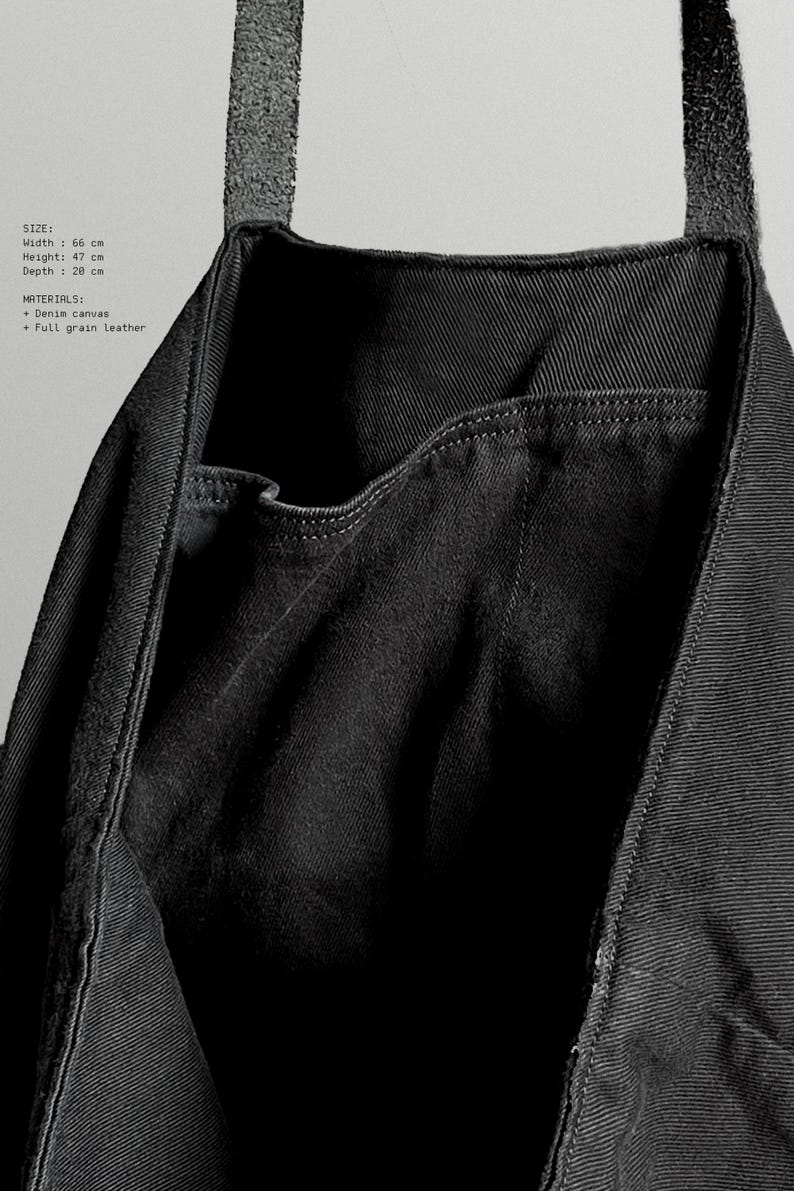 May include: Black denim canvas tote bag with a full-grain leather strap. The bag has a width of 66 cm, a height of 47 cm, and a depth of 28 cm. The bag features a pocket on the front.