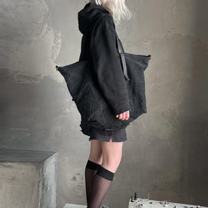 May include: A large black canvas tote bag with a textured finish and black shoulder straps. The bag features a spacious main compartment and is carried over the shoulder. The material appears durable and matte, providing a functional accessory for daily use.