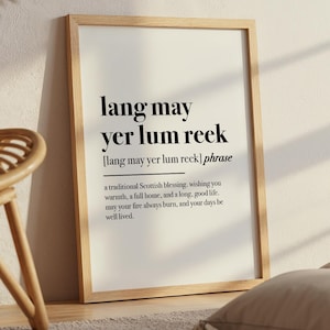 Puede incluir: Un cartel enmarcado con la frase escocesa "lang may yer lum reek" en negro. El cartel incluye una definición de la frase, una bendición escocesa tradicional. El marco es de madera clara.