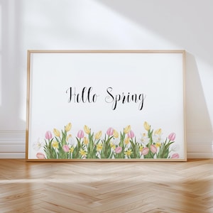 May include: A framed print with the words "Hello Spring" in elegant script. The bottom of the print features a watercolor illustration of tulips and daffodils in shades of pink, yellow, and white, set against a white background.
