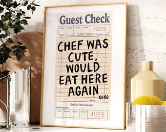 May include: A framed print with a white background and black text that reads "Guest Check" and "CHEF WAS CUTE, WOULD EAT HERE AGAIN" with a handwritten "XOXO" at the bottom. The print is on a countertop with a silver bowl and a yellow vase.