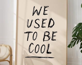 Könnte beinhalten: Ein beiger Poster mit schwarzem Text, der "WE USED TO BE COOL" lautet, mit einer schwarzen Linie unter dem Text. Der Poster ist in einem hellen Holzrahmen gerahmt und hängt an einer weißen Wand.