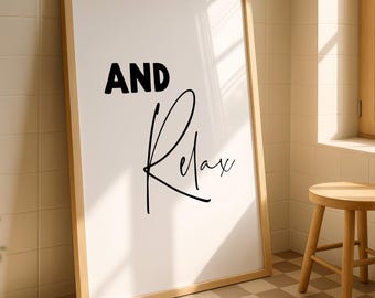 Puede incluir: Un cuadro enmarcado con las palabras "AND Relax" en escritura negra. La obra de arte tiene un marco de madera clara y está apoyada contra una pared de azulejos. Un pequeño taburete de madera se encuentra cerca, lo que sugiere un baño o un spa.