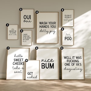 May include: A collection of framed art prints with humorous bathroom-themed quotes in black text on a white background. The prints vary in size and include phrases like "Nice Bum" and "Wash Your Hands You Detty Pig."