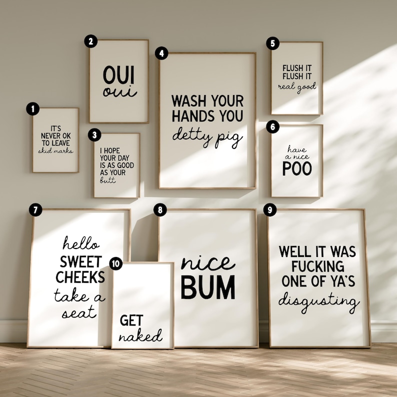 May include: A collection of framed art prints with humorous bathroom-themed quotes in black text on a white background. The prints vary in size and include phrases like "Nice Bum" and "Wash Your Hands You Detty Pig."