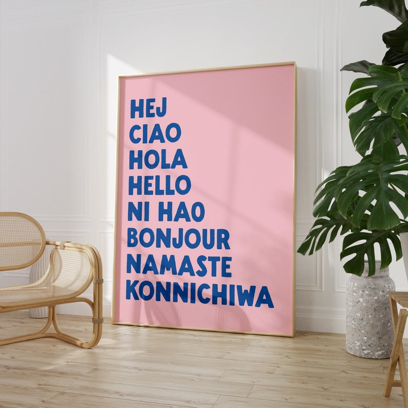 Peut inclure: Une affiche rose avec les mots "Hej", "Ciao", "Hola", "Hello", "Ni Hao", "Bonjour", "Namaste", et "Konnichiwa" &eacute;crits en bleu.