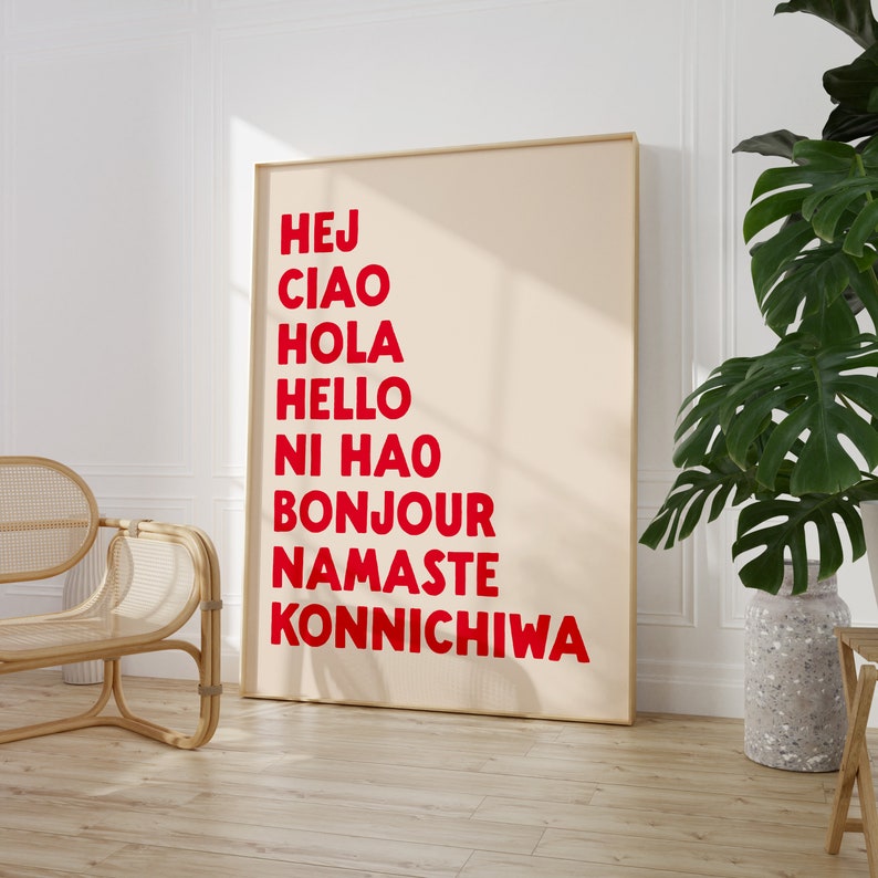 Peut inclure: Une affiche beige avec un cadre en bois, pr&eacute;sentant les mots "Hej", "Ciao", "Hola", "Hello", "Ni Hao", "Bonjour", "Namaste", et "Konnichiwa" en lettres rouges.