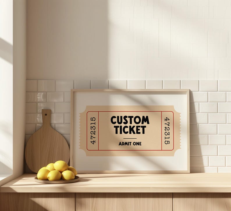 May include: A framed print featuring a custom ticket design. The ticket is tan with a red border and the words "CUSTOM TICKET" and "ADMIT ONE" in black. The print is displayed on a wooden surface with lemons and a cutting board.