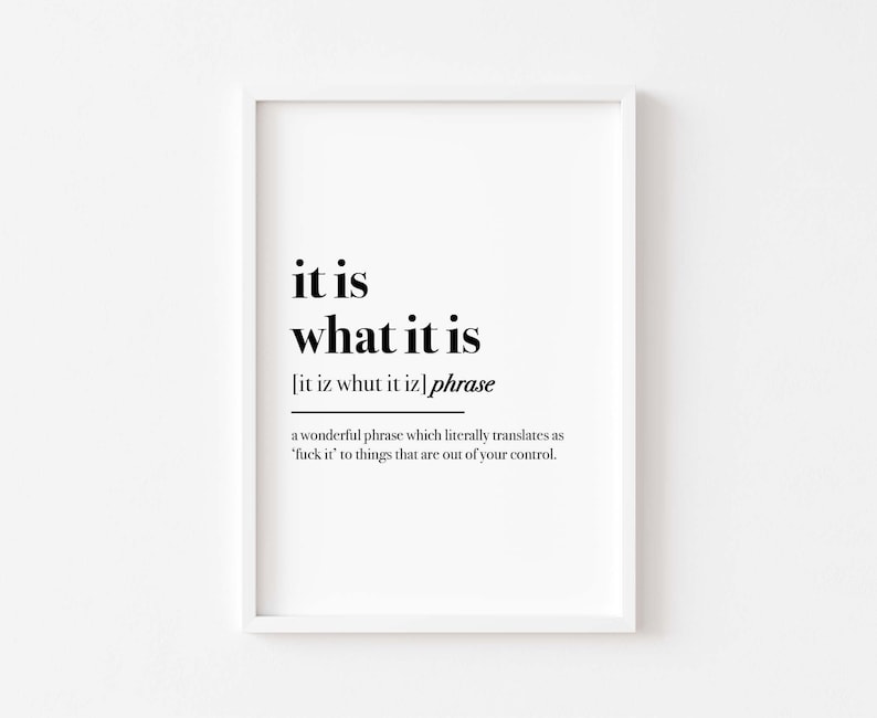 May include: A framed print with the phrase "it is what it is" in a bold, black font. The text includes a phonetic pronunciation and a definition, framed in a white border. The print's message is about accepting things beyond one's control.