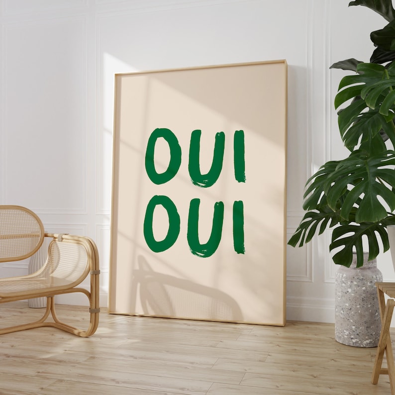 May include: A framed print with the text "OUI OUI" in green on a beige background.