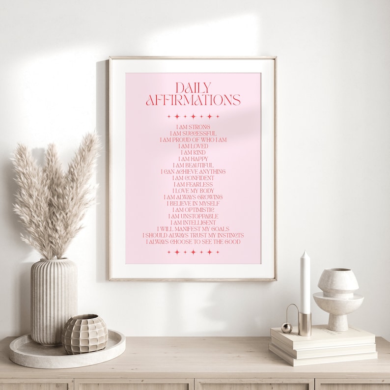 May include: A pink printable poster with the text "Daily Affirmations" in a bold, red font. The poster lists a series of positive affirmations, such as "I am strong", "I am successful", "I am loved", and "I am happy".