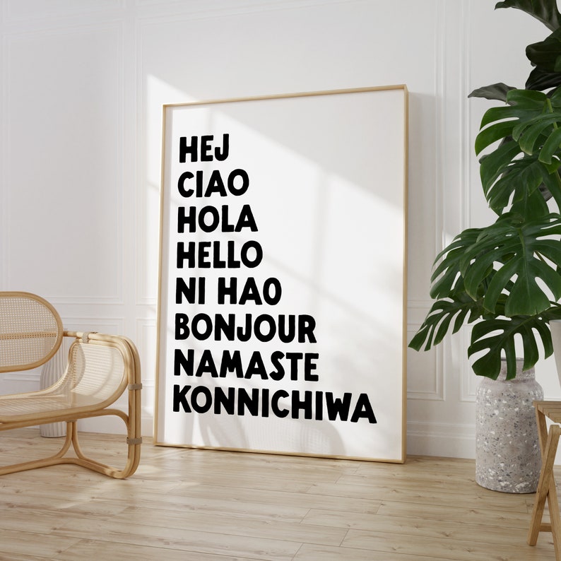 Peut inclure: Une impression murale d'art imprimable en noir et blanc avec les mots "Hej", "Ciao", "Hola", "Hello", "Ni Hao", "Bonjour", "Namaste" et "Konnichiwa" &eacute;crits verticalement sur un fond blanc.