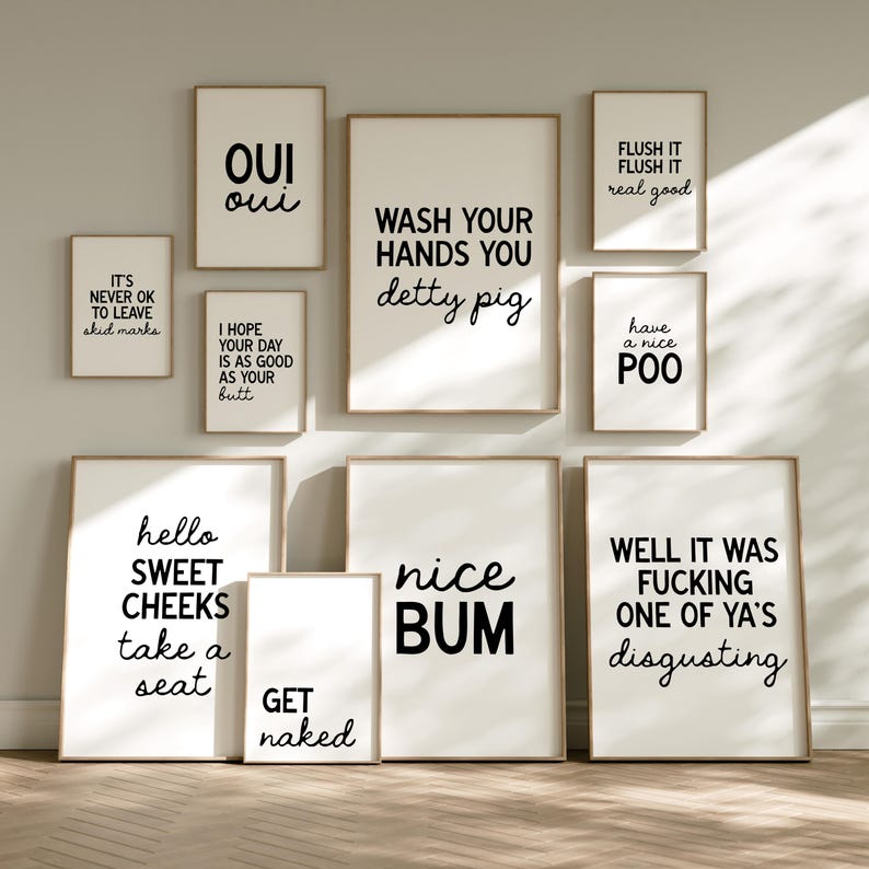 May include: A collection of framed art prints with humorous bathroom-themed quotes in black text on a white background. The prints include phrases like "Wash Your Hands You detty pig" and "Hello Sweet Cheeks take a seat."