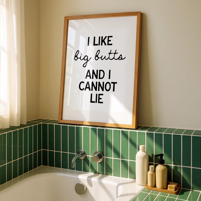 May include: A framed print with the text "I LIKE big butts AND I CANNOT LIE" in black font. The print is in a light brown wooden frame and is displayed above a bathtub with green tile.