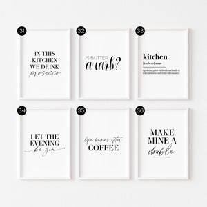 May include: Six white framed prints with black text on a white background. The prints feature kitchen-themed quotes and sayings, such as "In this kitchen we drink prosecco" and "Life begins after coffee".