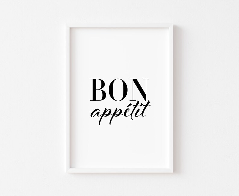 May include: A framed print with the words "BON app&eacute;tit" in black script and serif font. The print is in a white frame and set against a white background. The phrase is a French expression often used before a meal.