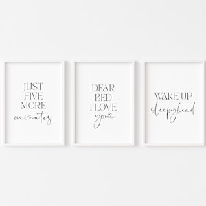 May include: Three white framed prints with black text. The first print says "Just five more minutes". The second print says "Dear bed I love you". The third print says "Wake up sleepyhead".