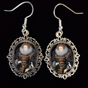 May include: Silver filigree earrings with oval glass cabochons featuring a portrait of Queen Elizabeth I in a black and gold gown with a white ruff.
