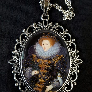 May include: A silver pendant necklace with an oval cameo featuring a portrait of Queen Elizabeth I. The cameo is surrounded by an ornate silver frame.