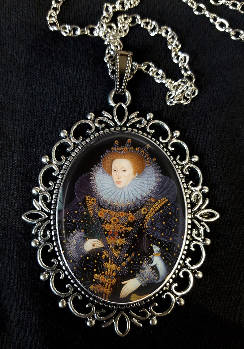 May include: A silver pendant necklace with an oval cameo featuring a portrait of Queen Elizabeth I. The cameo is surrounded by an ornate silver frame.
