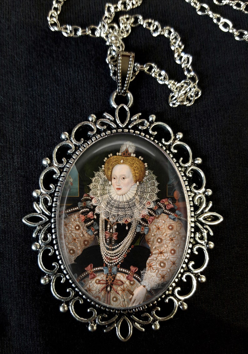 May include: Silver pendant necklace featuring a cameo of Queen Elizabeth I wearing a white lace ruff and pearl jewellery. The cameo is set in a silver oval frame with ornate scrollwork.