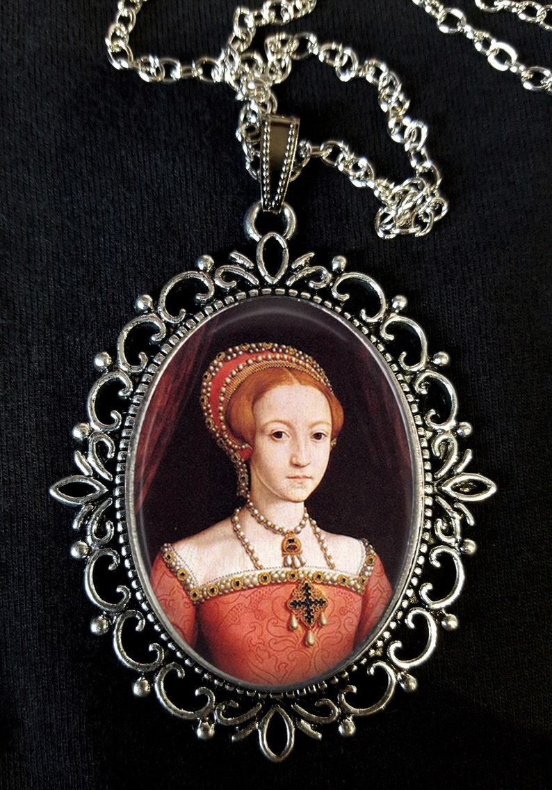 May include: A silver pendant necklace featuring a cameo of a woman in a red dress and a pearl necklace. The cameo is set within an ornate silver frame.