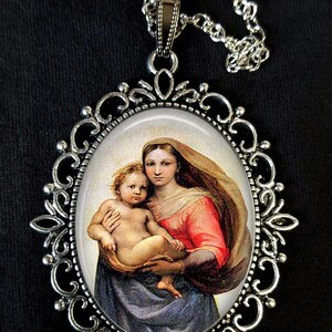 Op de afbeelding: Een zilveren ketting met een cameo-hanger met een schilderij van de Madonna en Kind. De hanger is ovaalvormig en heeft een gedetailleerd filigraan frame.