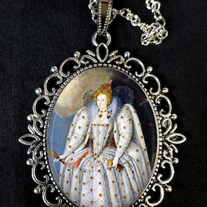 May include: A silver pendant necklace with an oval cameo featuring a portrait of Queen Elizabeth I in a white and gold gown. The cameo is set in a silver filigree frame.